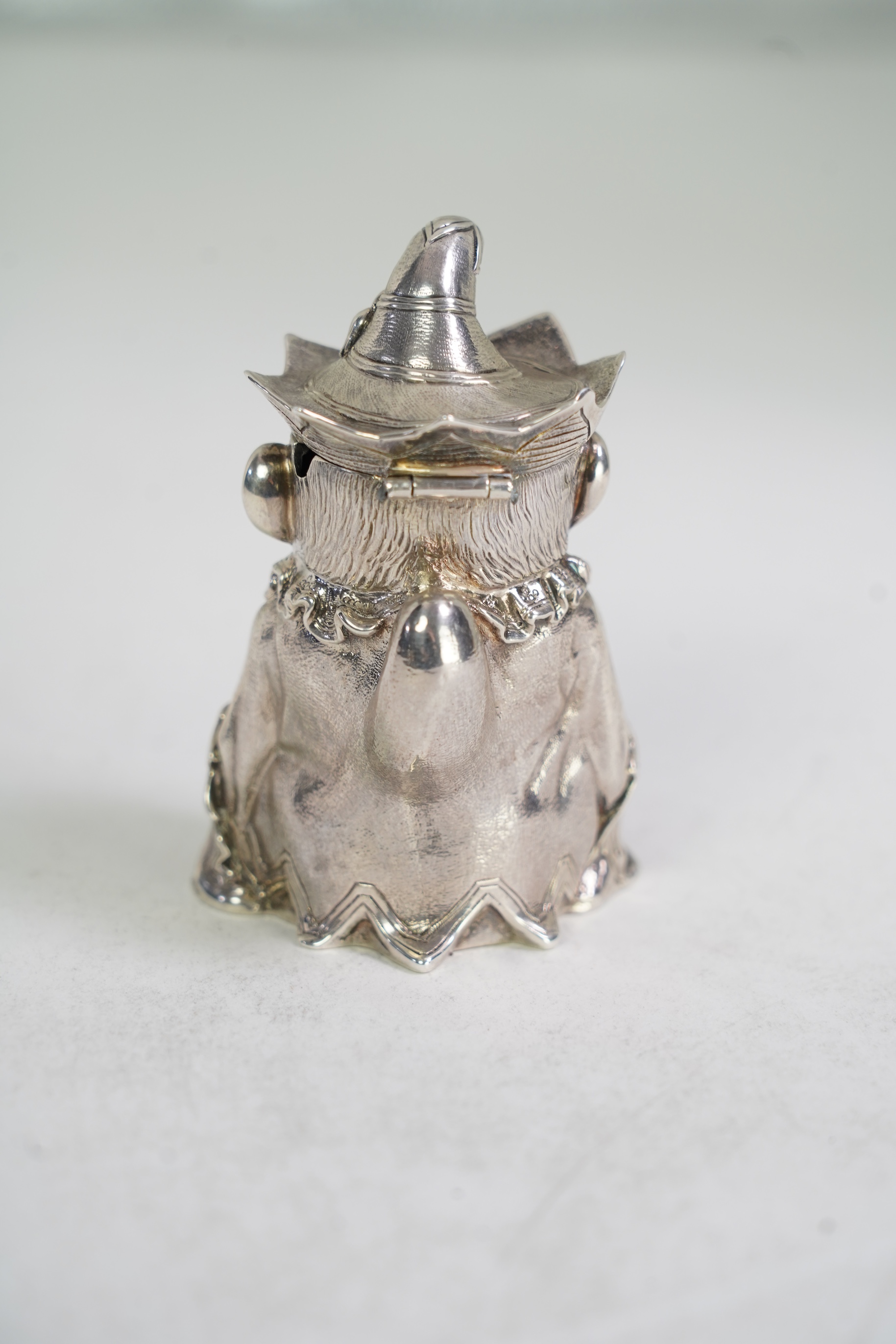 A rare Victorian novelty cast silver mustard pot, modelled as seated cross-legged Mr. Punch, holding a wine glass and smoking a pipe, by Robert Hennell III